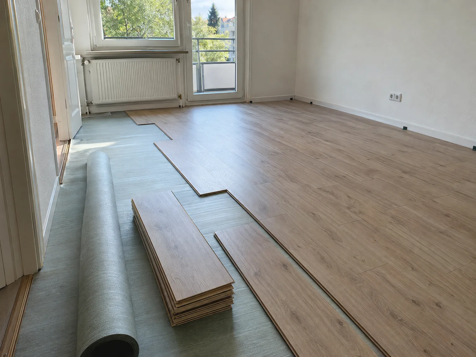 Laminat-Dielen in Holzoptik liegen bereit zur Verlegung in hellem Raum