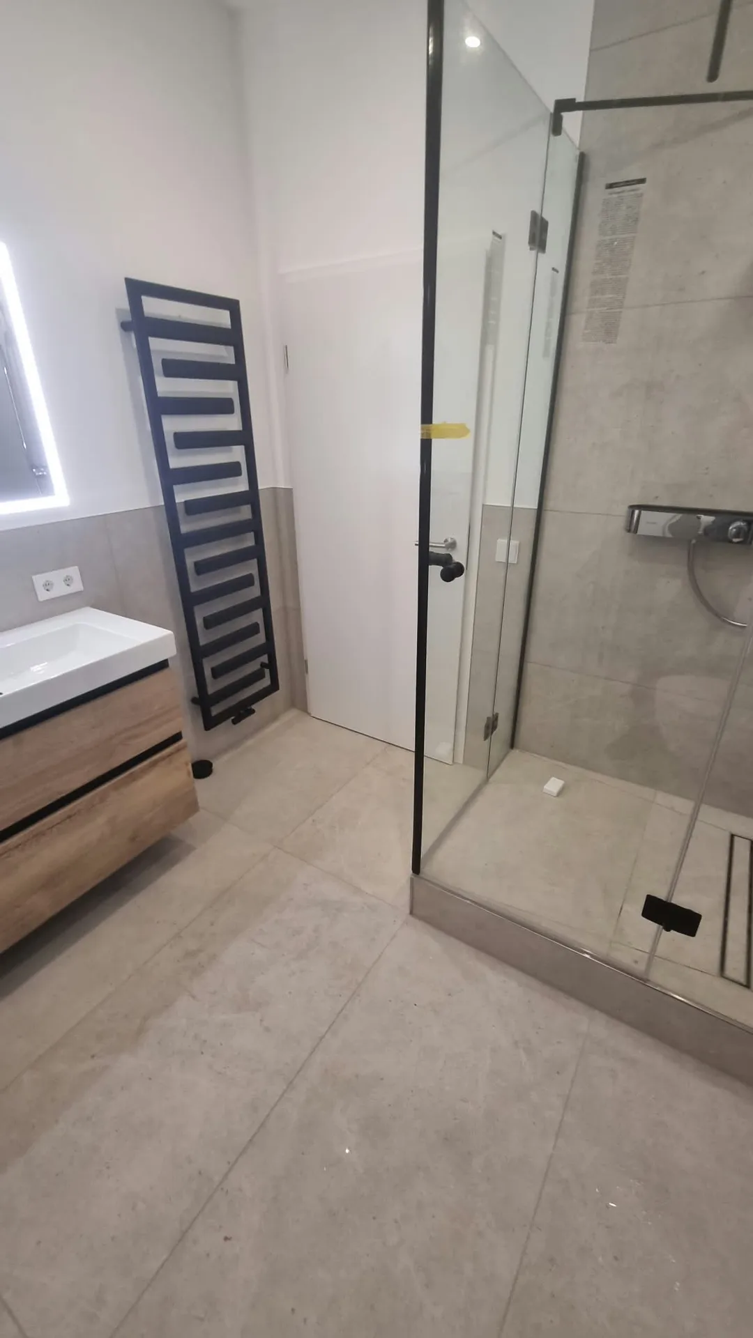 Modernes Badezimmer mit begehbarer Dusche, Betonoptik-Bodenfliesen und schwarzem Badheizkörper