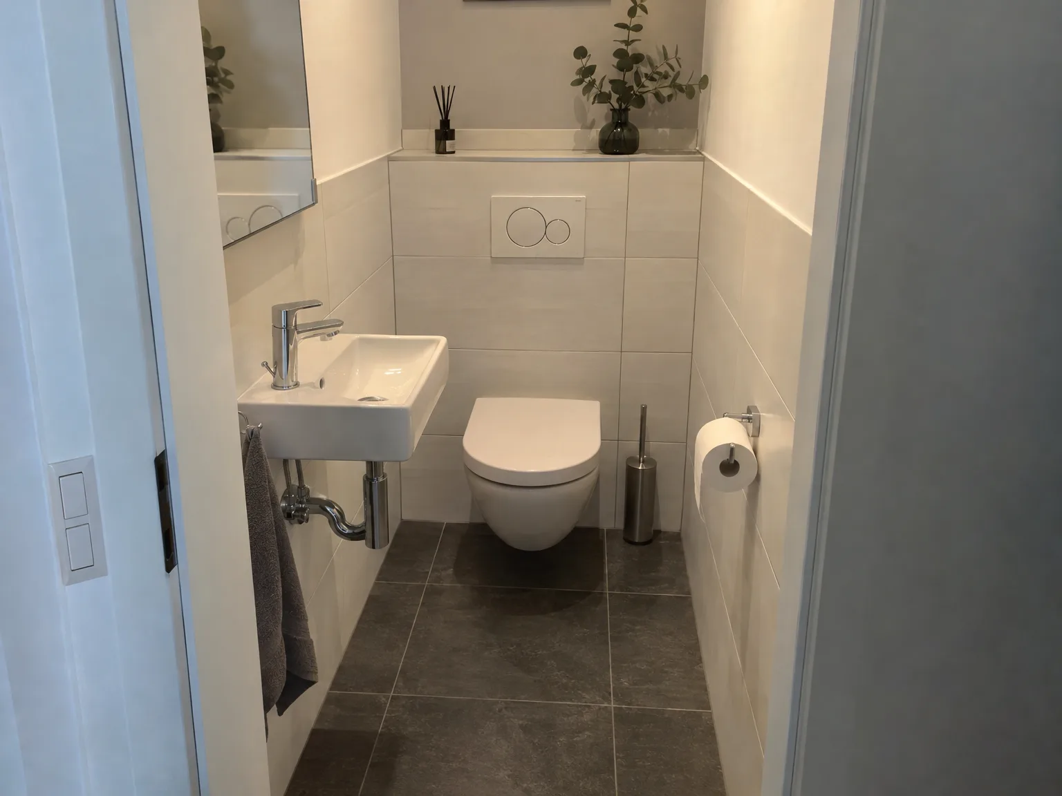 Renoviertes modernes Gäste-WC mit beigen Wandfliesen, schwarzem Fliesenboden und schwebendem WC