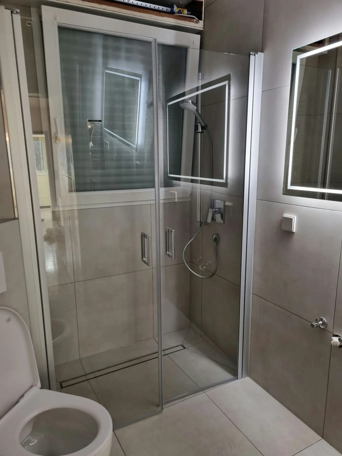Modernes Badezimmer mit Glasduschkabine und großformatigen Fliesen