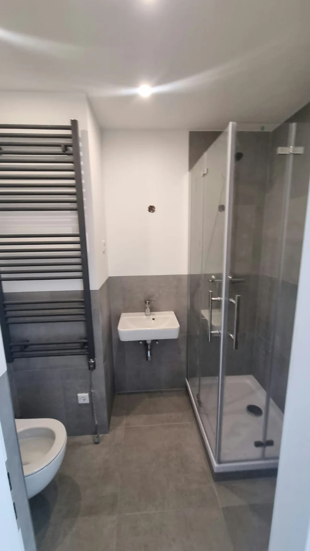 Renoviertes Badezimmer mit bodengleicher Dusche und modernen Fliesenarbeiten
