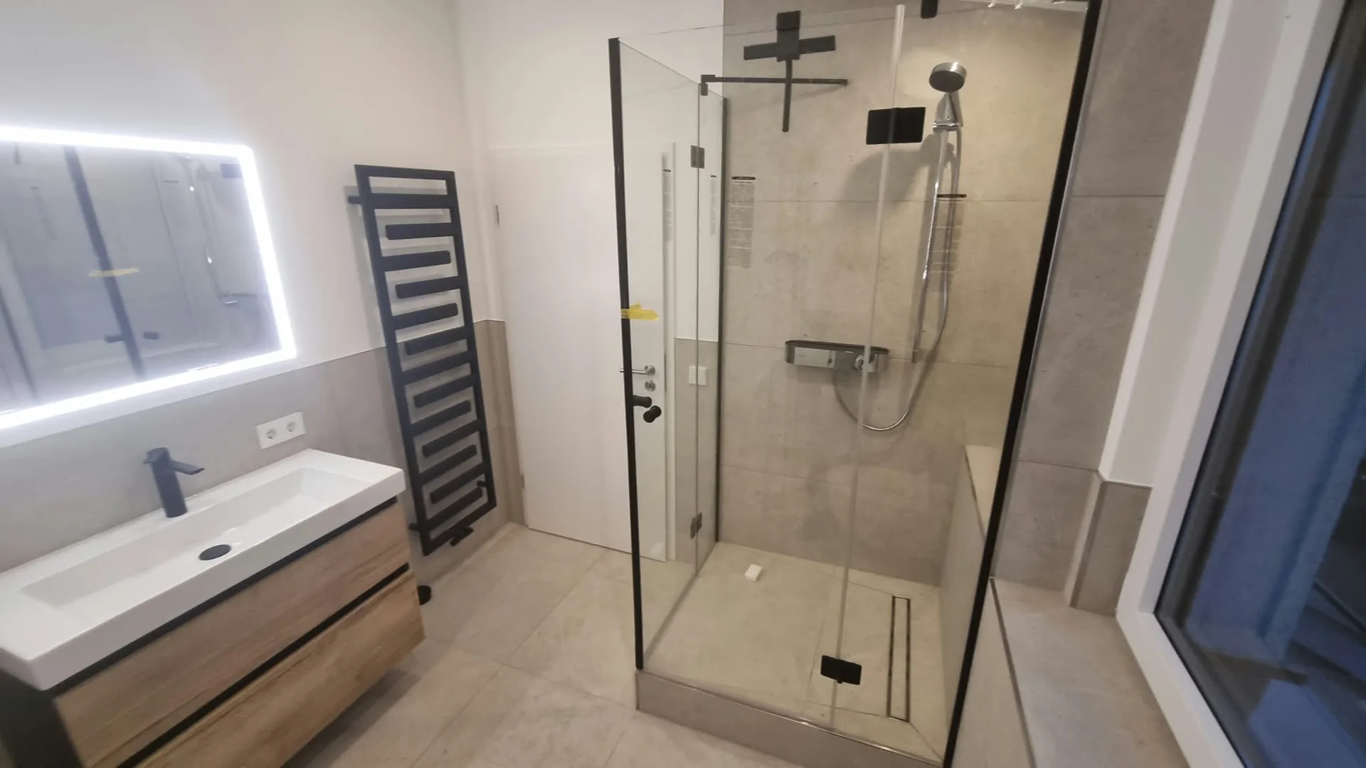 Renoviertes Badezimmer mit Glasdusche und großformatigen Fliesen