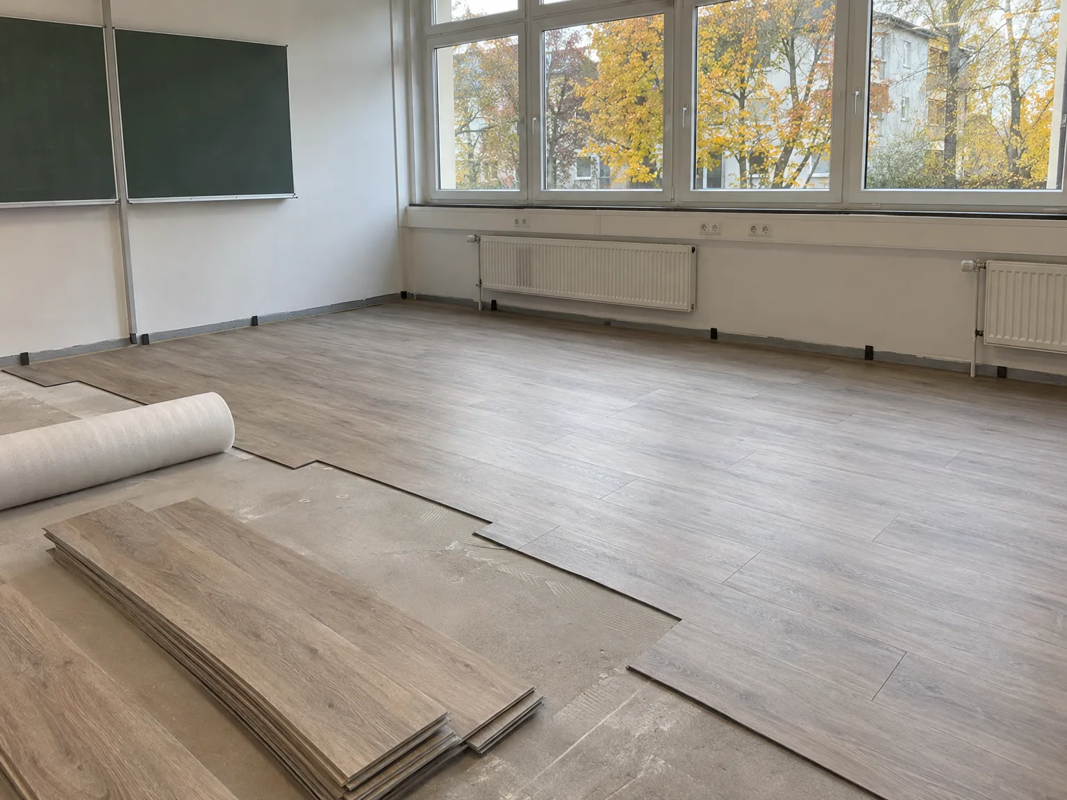 Laminatboden wird in Klassenzimmer verlegt mit ausgerolltem Material und Planken
