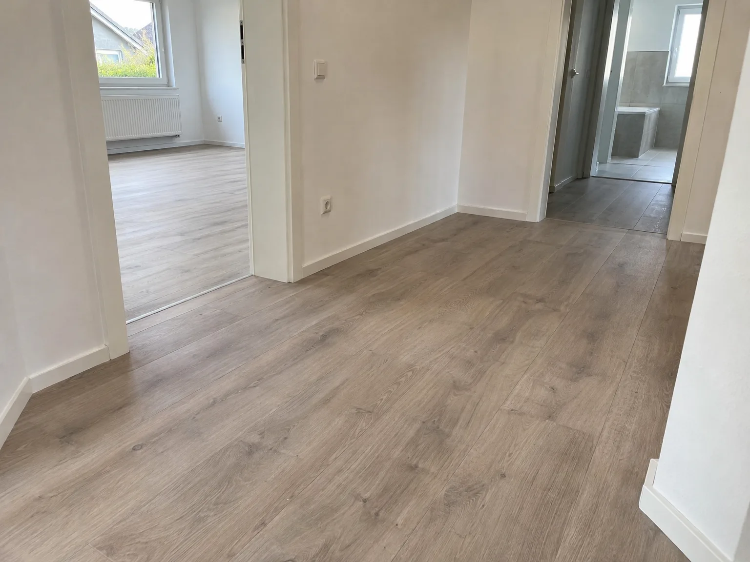 Heller neu verlegter Laminatboden mit Holzmaserung im fertig renovierten Raum
